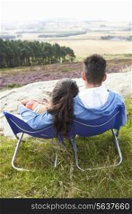 Young Couple Sitting In Chairs On Camping Trip