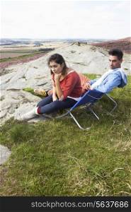 Young Couple Sitting In Chairs On Camping Trip