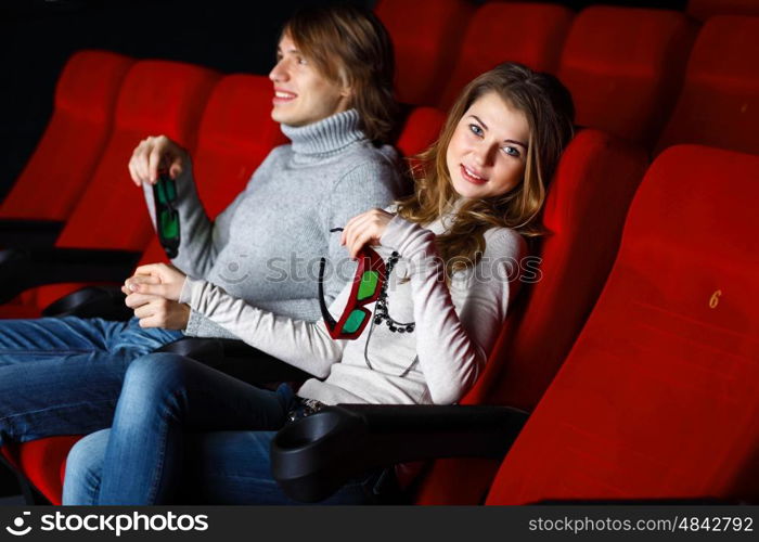 Young couple sitting in cinema and watching movie