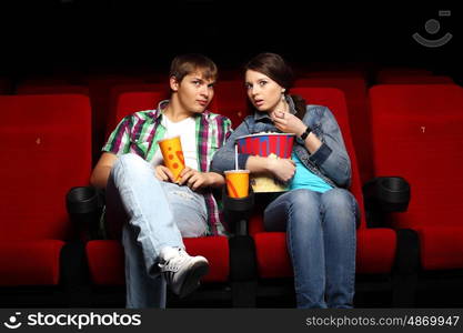 Young couple sitting in cinema and watching movie