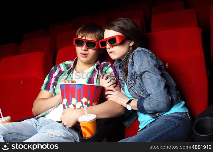 Young couple sitting in cinema and watching movie