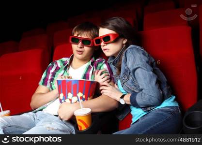 Young couple sitting in cinema and watching movie