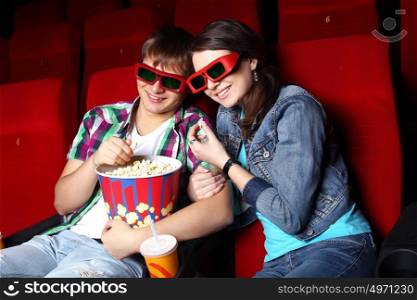 Young couple sitting in cinema and watching movie