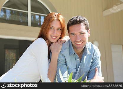 Young couple sitting in front of their new house