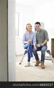 Young Couple Sitting In Property Being Renovated
