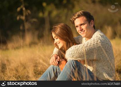 Young couple sitting in rural setting, smiling