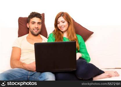 Young couple sitting in the couch and watching something on the computer