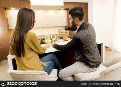 Young couple sitting in the kitchen with his back and drinking white wine