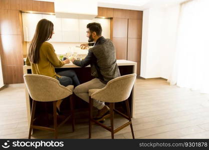 Young couple sitting in the kitchen with his back and drinking white wine