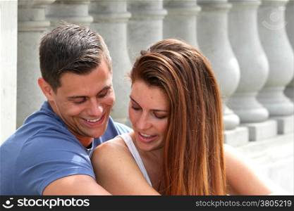 Young couple sitting on a bridge.