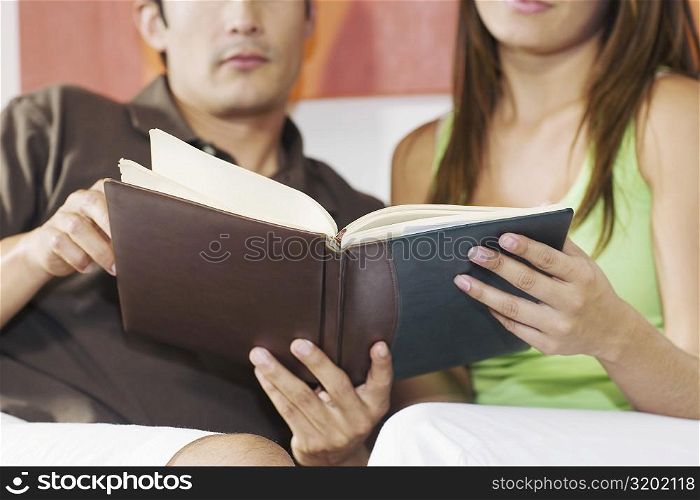 Young couple sitting on a couch and holding a book