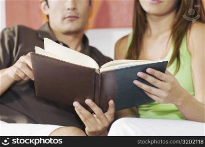 Young couple sitting on a couch and holding a book