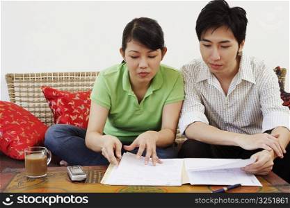 Young couple sitting on a couch and reading documents