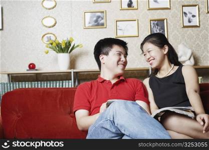 Young couple sitting on a couch looking at each other