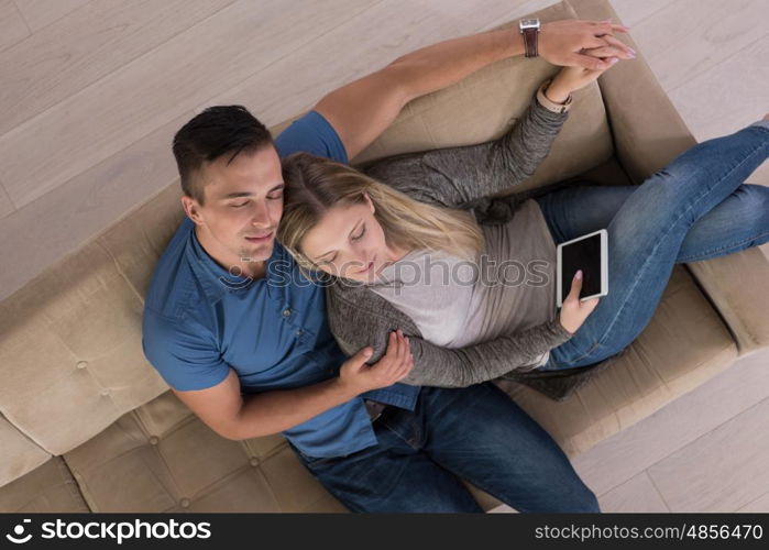 Young couple sitting on a sofa in the luxury living room, using a tablet computer top view