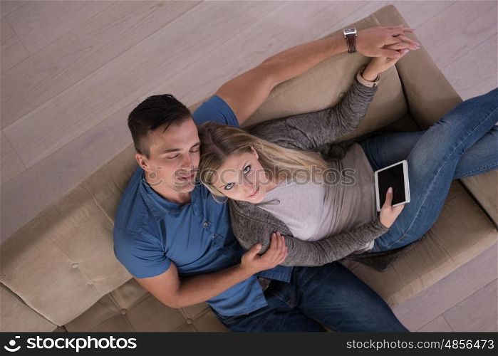 Young couple sitting on a sofa in the luxury living room, using a tablet computer top view
