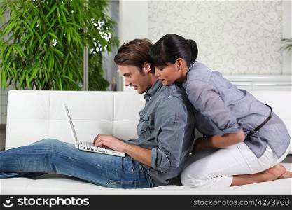 Young couple sitting on a sofa using a laptop