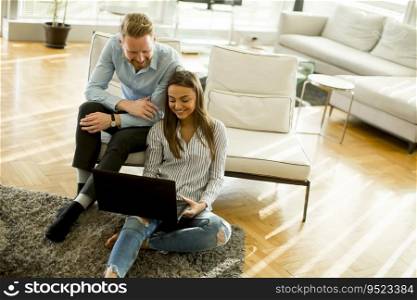 Young couple sitting on a sofa, using a laptop in a relaxed atmosphere in the room