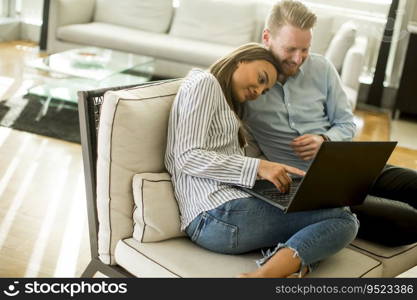 Young couple sitting on a sofa, using a laptop in a relaxed atmosphere in the room