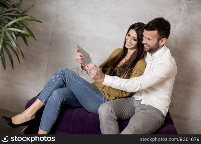 Young couple sitting on a sofa with a digitaltablet