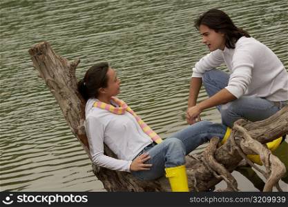 Young couple sitting on a tree over a lake