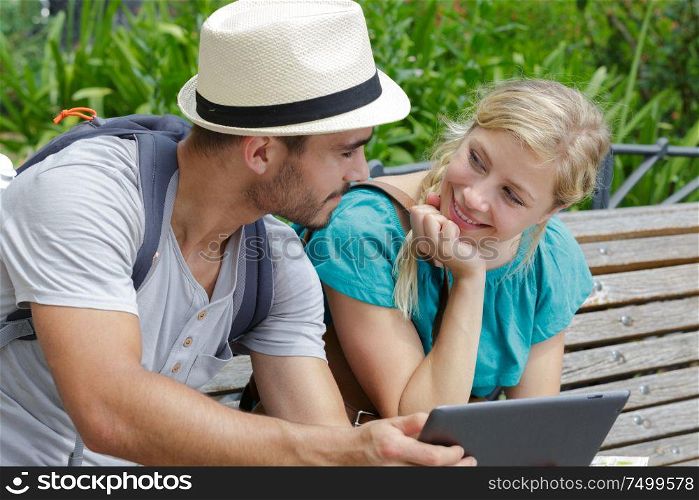 young couple sitting on beach using tablet