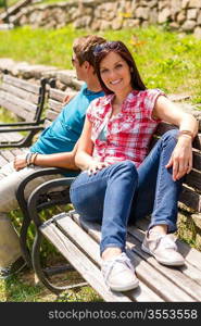 Young couple sitting on bench in park resting happy smiling