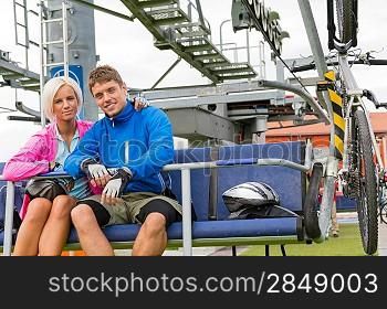 Young couple sitting on chair lift waiting for departing