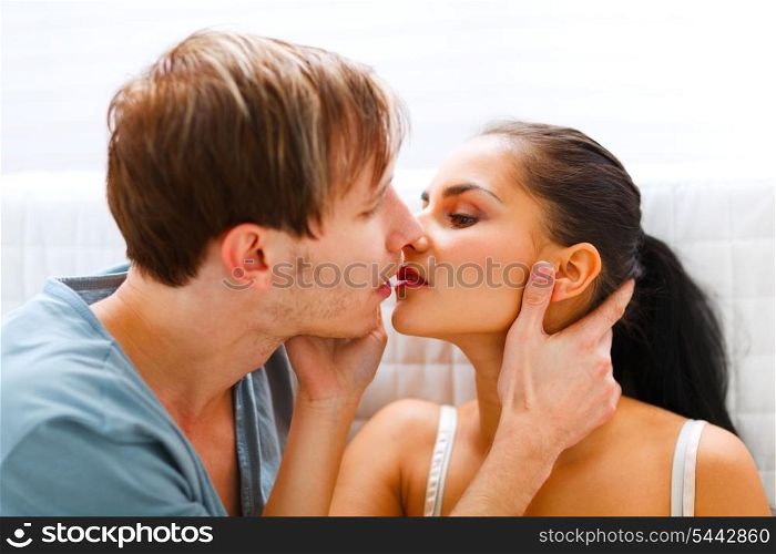 Young couple sitting on couch and kissing&#xA;