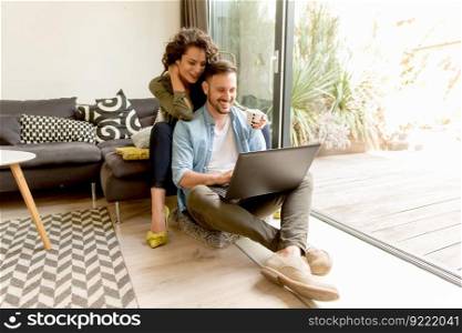 Young couple sitting on floor and using notebook. Online shopping