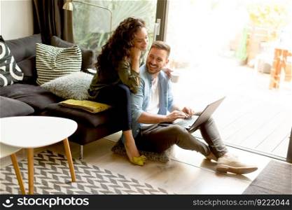Young couple sitting on floor and using notebook. Online shopping