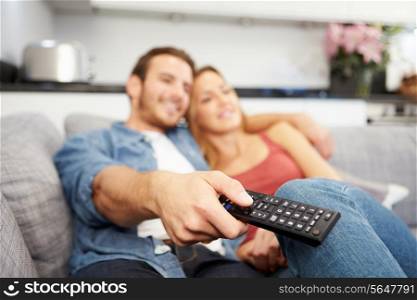 Young Couple Sitting On Sofa Watching Television