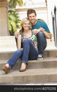 Young Couple Sitting On Steps Of Building