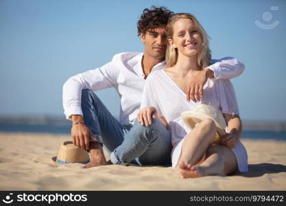 young couple sitting on summer beach