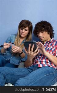 Young couple sitting on the bed making an online purchase with the tablet. Couple making online purchase with tablet