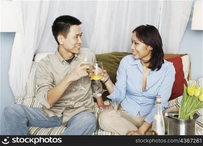 Young couple sitting on the bed toasting with wineglasses