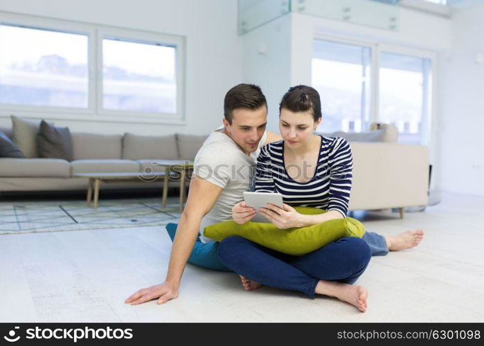 Young Couple sitting on the floor and using interent on digital tablet