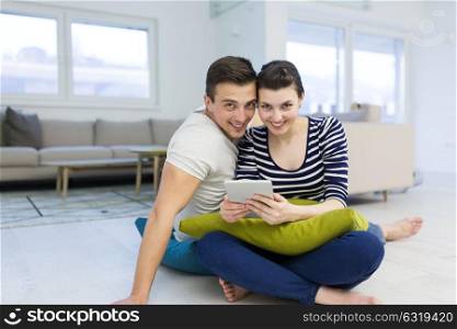 Young Couple sitting on the floor and using interent on digital tablet