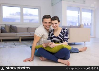 Young Couple sitting on the floor and using interent on digital tablet