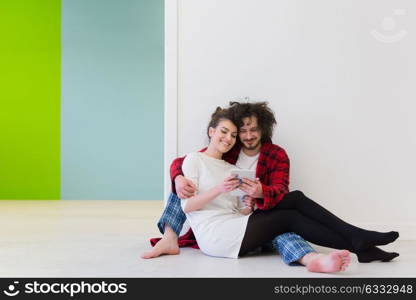 Young Couple sitting on the floor and using interent on digital tablet