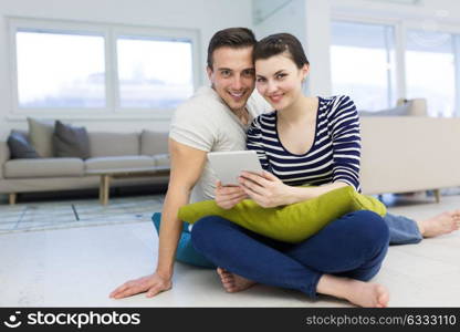 Young Couple sitting on the floor and using interent on digital tablet