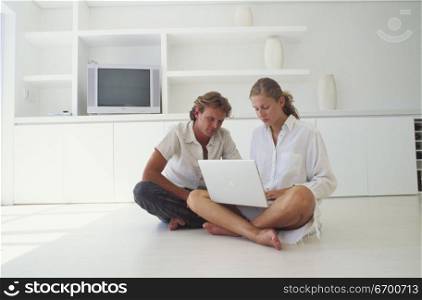 Young couple sitting on the floor with a laptop