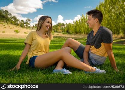 Young couple sitting on the grass and having fun