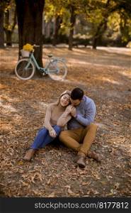 Young couple sitting on the ground in autumn park
