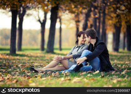 Young couple sitting on the ground in the autumn park