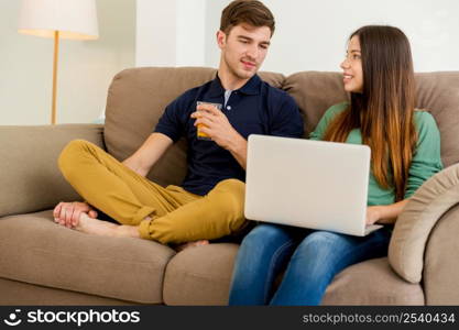 Young couple sitting on the sofa and watching something on a laptop