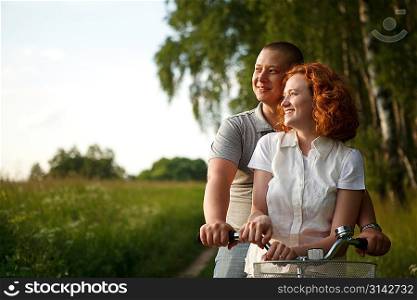 Young couple sitting one bicycle and looking at something
