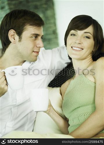 Young couple sitting together and holding coffee cups