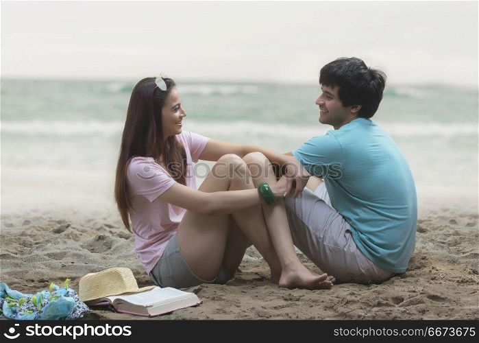 Young couple sitting together on beach