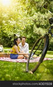 Young couple sitting together on picnic blanket